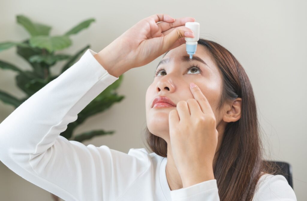 Woman putting eye drops into her left eye.