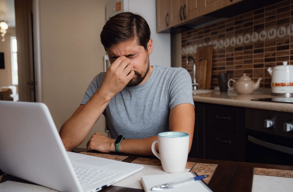 Man sitting at his computer rubbing his eyes