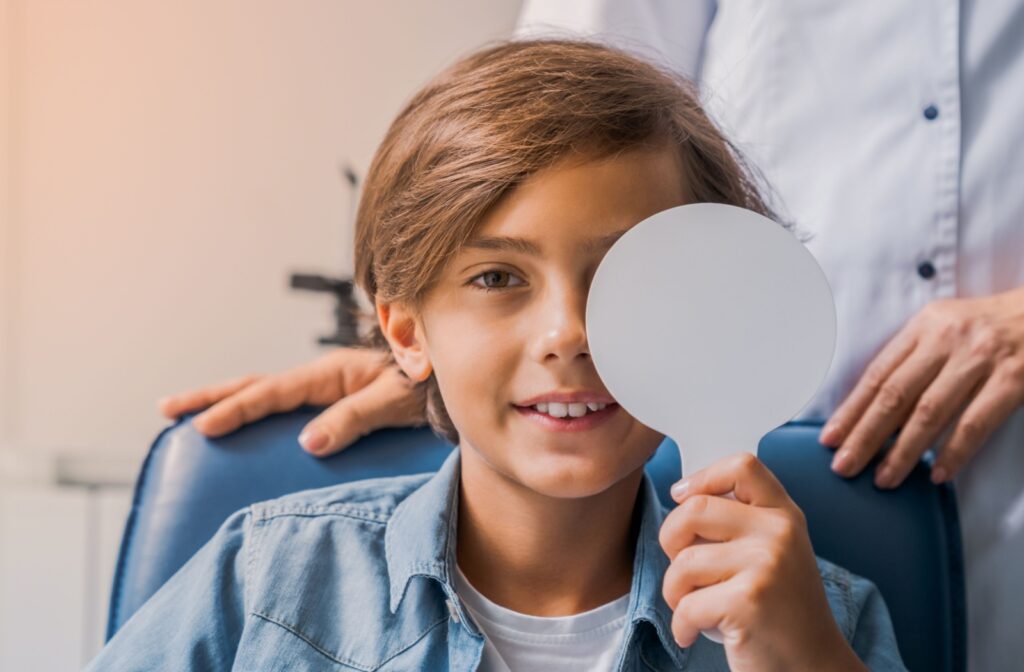 Child covering eye during vision exam at the optometrist clinic.